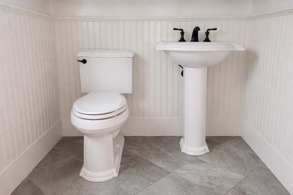 New toilet and pedestal sink installed as part of bathroom fixture replacement.