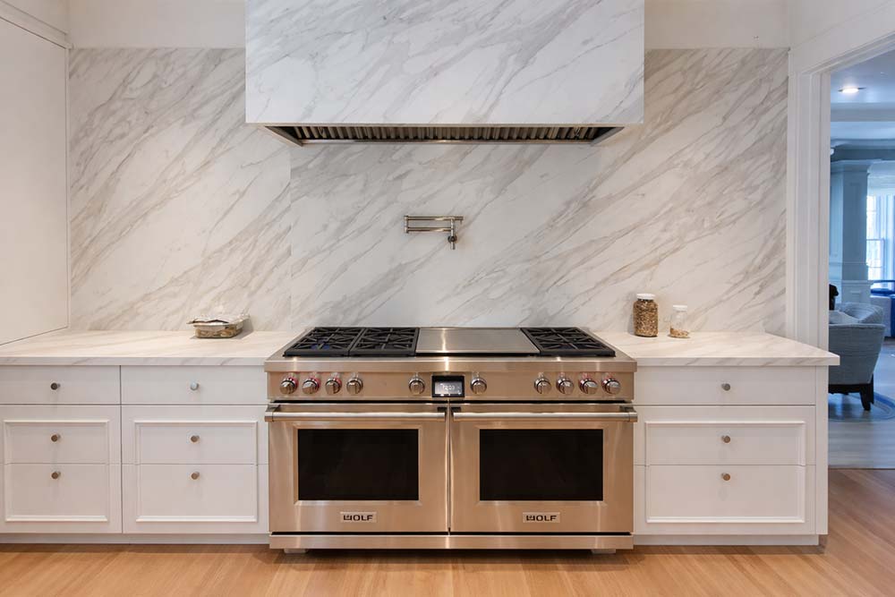 Custom kitchen remodel featuring professional gas range and marble backsplash