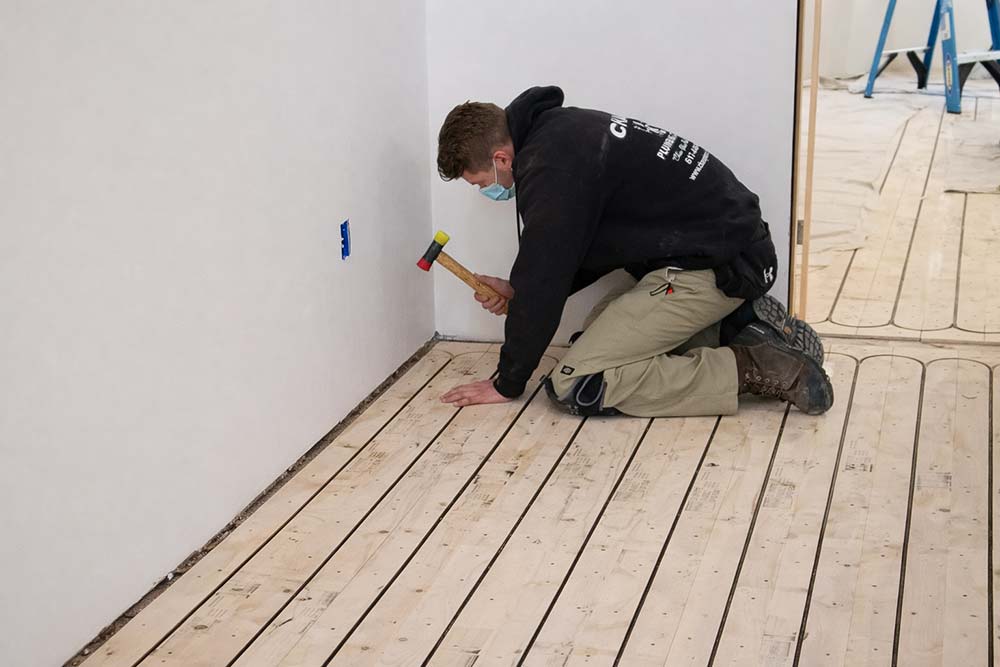 Professional installing radiant floor heating panels during residential construction.
