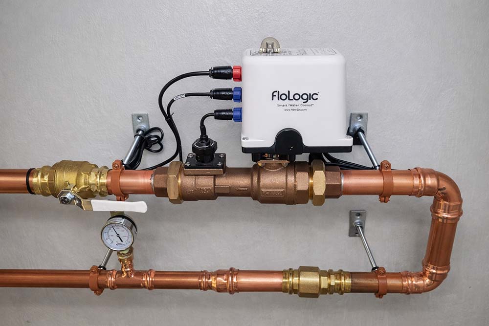 Whole-house automatic water shut-off valve system installed on copper main line with FloLogic smart controller and pressure gauge.