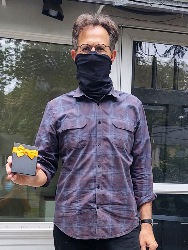August 2020 Chase Plumbing sign contest winner holding prize outside a home.