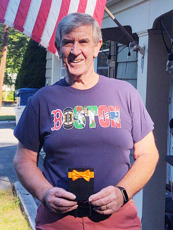 August 2021 Chase Plumbing sign contest winner holding a prize outside a residence.