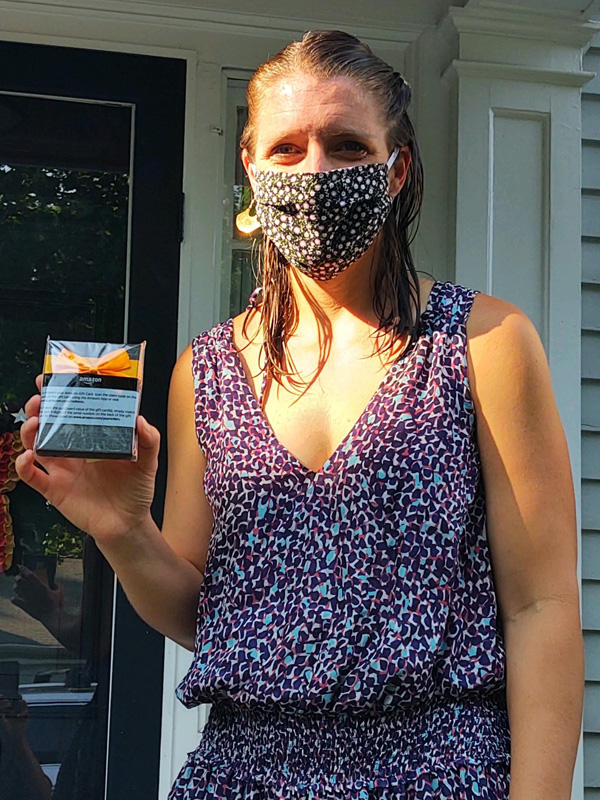 July 2020 Chase Plumbing sign contest winner holding a prize outside a home entrance.