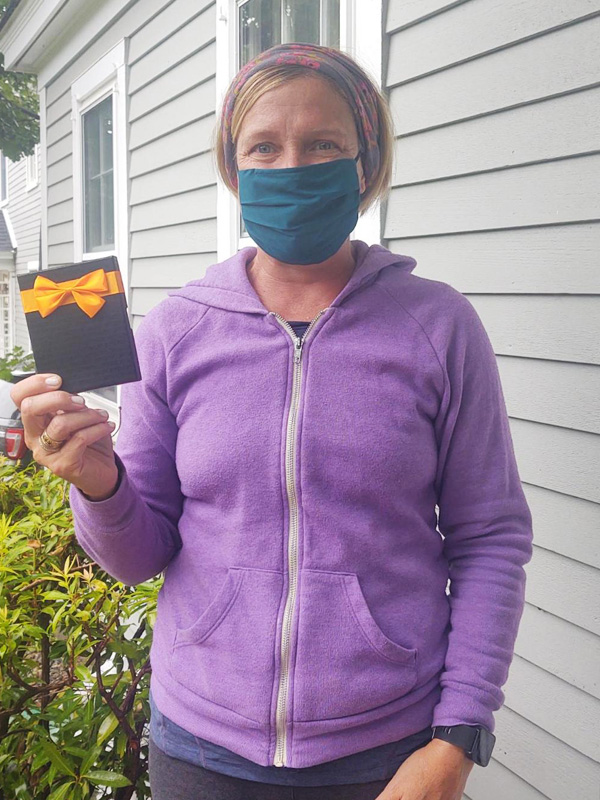 July 2021 Chase Plumbing sign contest winner holding a prize outside a home.