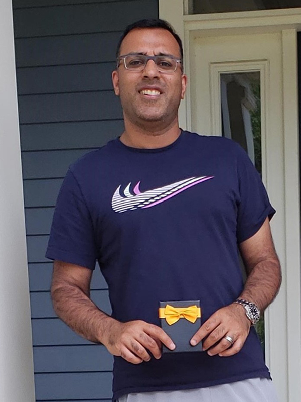 June 2020 Chase Plumbing sign contest winner holding a prize outside a home entrance.