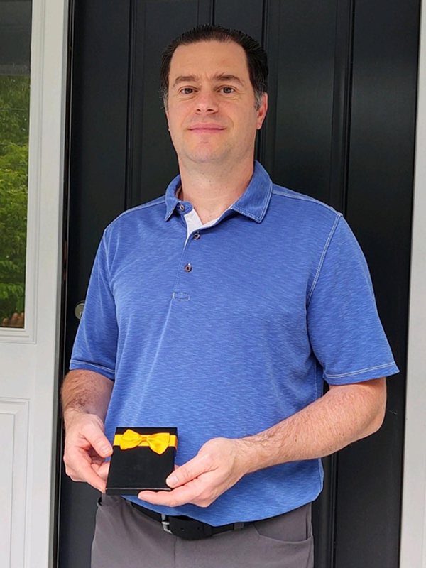 May 2020 Chase Plumbing sign contest winner holding a prize outside a home entrance.