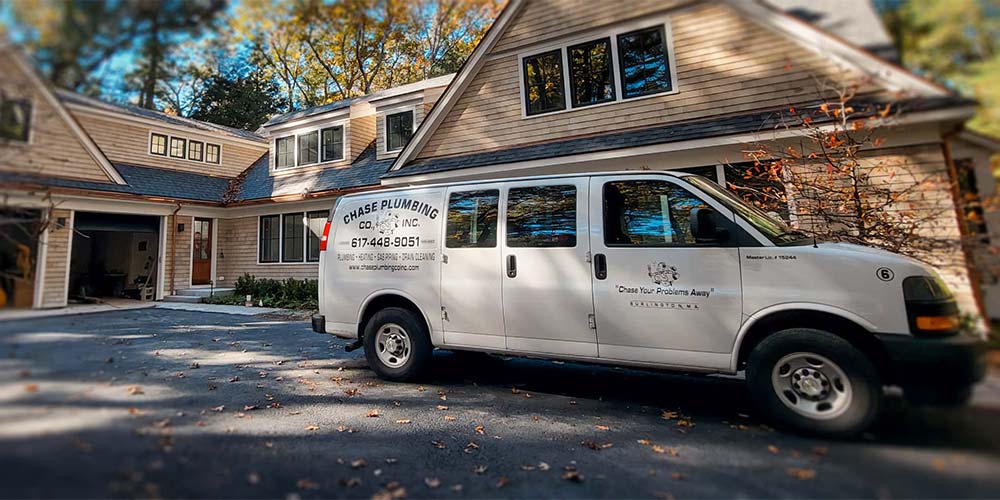 Chase Plumbing Co. service van parked in the driveway of a residential home, ready for plumbing service.