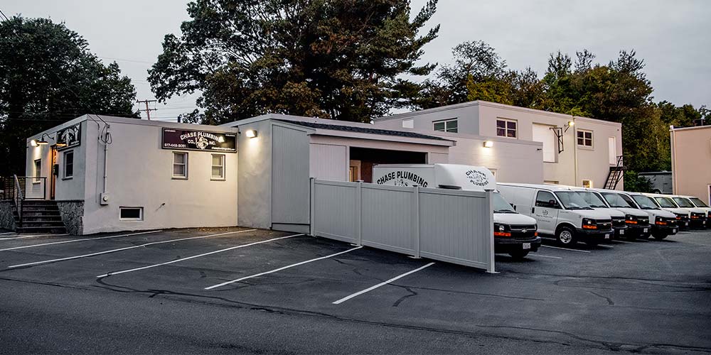 Exterior view of Chase Plumbing headquarters with service vans parked outside.